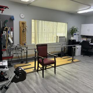 A well-equipped physical therapy room featuring exercise equipment and a comfortable chair.