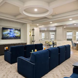 A modern living room with a home theater setup, featuring blue seating and a large television.