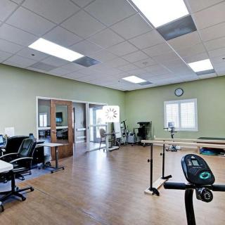 A physical therapy room with exercise equipment and open space.