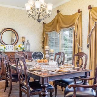 An elegant dining room with traditional wooden furniture, a formal table setting, and a chandelier.