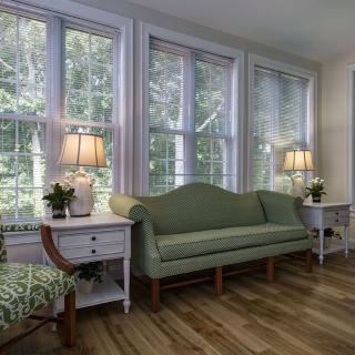 A cozy living room with large windows, a green sofa, and elegant lighting.