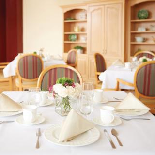 An elegantly arranged dining table ready for guests, featuring crisp white linens and decorative napkins.
