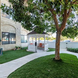 A serene garden with a gazebo, tree, and winding pathway beside a house.