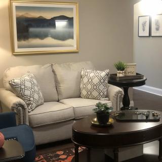 A cozy living room with a sofa, decorative cushions, and a framed landscape painting on the wall.