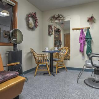 A cozy hair salon's waiting area with wicker chairs and decorative wall hangings.