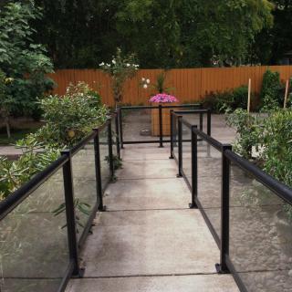 A serene garden walkway lined with plants and bordered by a wooden fence.