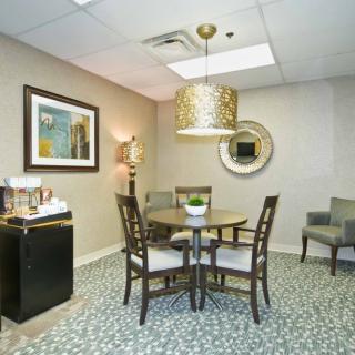 A modern office waiting area with a round table, chairs, and decorative elements.