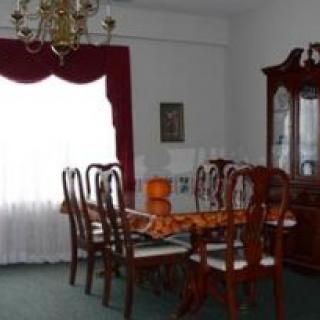 A traditional dining room featuring a wooden table, chairs, chandelier, and decorative cabinet.