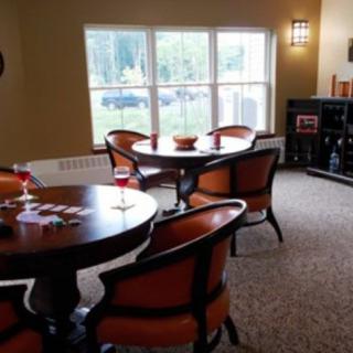 A cozy dining area with round tables and chairs, illuminated by natural light from a large window.