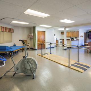 A spacious therapy room equipped with exercise apparatus and rehabilitation tools.