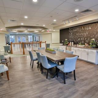 A modern dining area with a long table and comfortable seating, featuring stylish decor and wooden flooring.