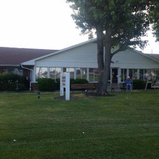 A view of a residential building surrounded by grass and a tree.