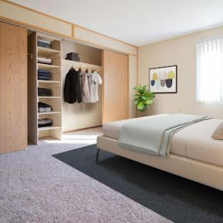 A modern and minimalist bedroom featuring a neatly arranged closet, comfortable bedding, and a touch of greenery.