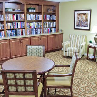 A cozy library corner with bookshelves, a round table, and comfortable seating.