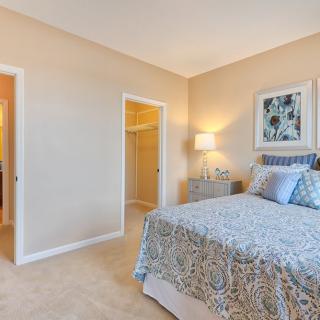 A cozy and elegantly decorated bedroom with a bed, bedside table, and framed artwork.