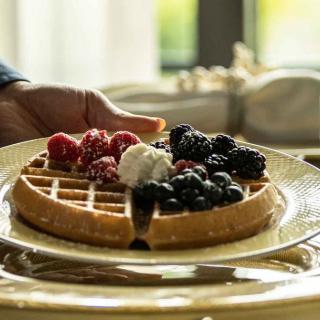 A delicious waffle topped with fresh berries and a dollop of cream served on a plate.