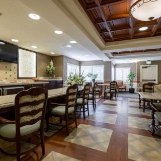 A spacious and elegantly designed dining area with wooden chairs and a polished floor, featuring warm lighting and tasteful decor.