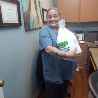 A cheerful individual holding a bag in an office setting.