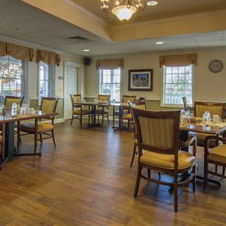An elegant dining area with wooden floors and neatly arranged tables and chairs.