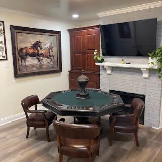 A cozy room featuring a poker table with chairs, a wall-mounted TV above the fireplace, and artwork on the wall.