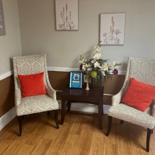 A cozy corner featuring elegant chairs, a decorative table with flowers, and artwork on the walls.