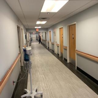 A quiet corridor in a hospital, featuring lined doors and medical equipment.