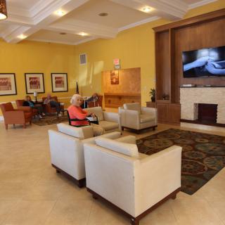A cozy lounge area with comfortable seating, a television, and decorative artwork on the walls.