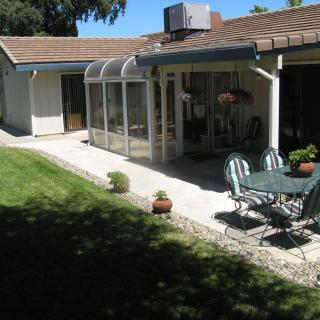 A house with a sunroom, patio set, and well-maintained lawn.