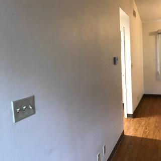 A view of a hallway with a light-colored wall and a doorway.