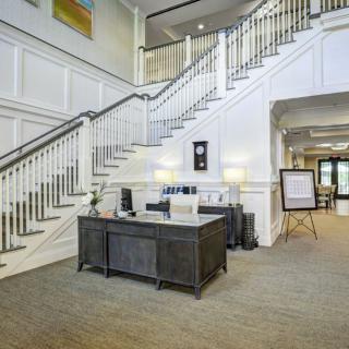 A spacious lobby featuring a grand staircase and a reception desk.