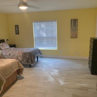 A spacious bedroom with yellow walls featuring two beds and a dresser.