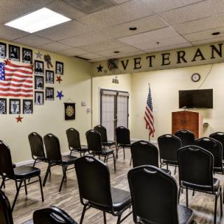 A meeting room set up with chairs, adorned with an American flag and photographs honoring veterans.