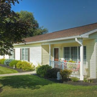 A suburban house with a front lawn and porch on a sunny day.