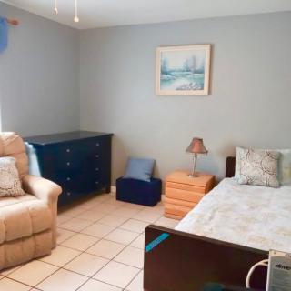 A cozy bedroom with a bed, recliner chair, and dresser.
