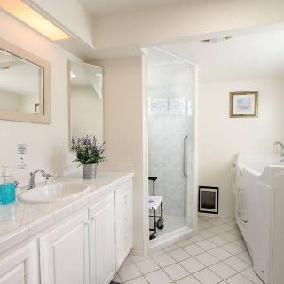 A bright and clean bathroom featuring a double vanity, a large mirror, and a glass-enclosed shower.