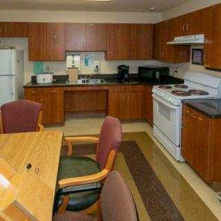 A kitchen with wooden cabinets, dining table, and standard appliances.