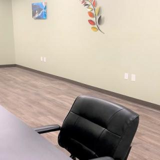 An empty office space with a black chair, table, and wall decor.
