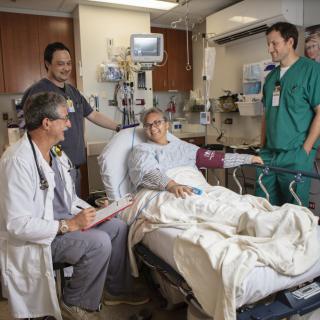 A group of medical professionals attending to a patient in a hospital room.