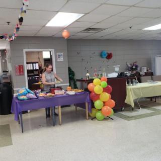 An indoor party setup with colorful balloons, tables, and food.