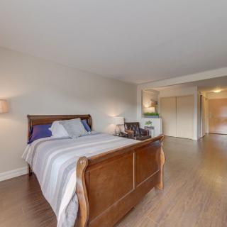 A cozy bedroom with a wooden bed frame, lamp, and hardwood floors.