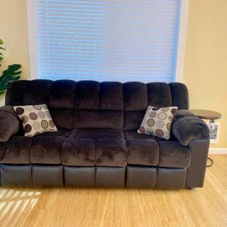 A plush dark sofa with patterned cushions in a cozy living room setting.