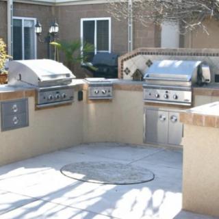 Outdoor kitchen with multiple grills on a patio.