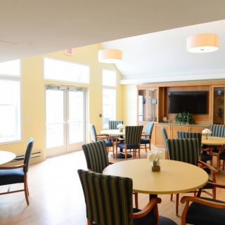 A bright and modern dining area with round tables and cushioned chairs.
