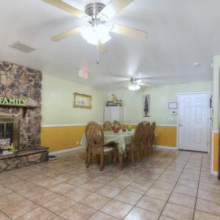 A dining room with a long table and chairs, featuring a stone fireplace and ceiling fans.