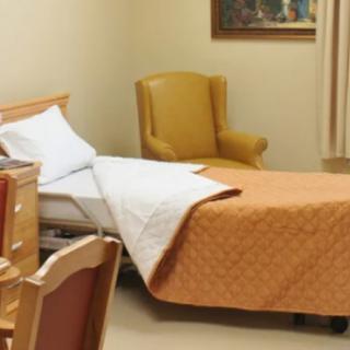 A simple room with a hospital bed and an armchair.
