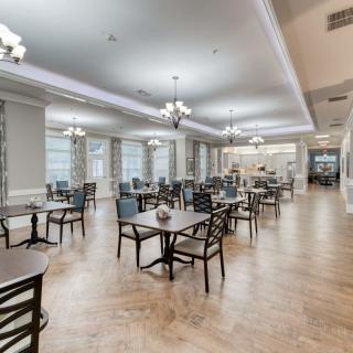 A spacious and elegantly designed dining area features neatly arranged tables and chairs under stylish lighting.