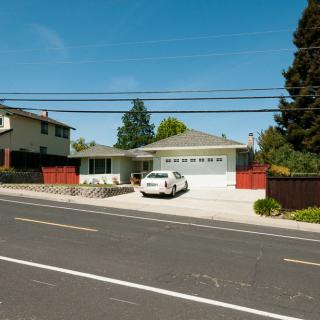 A suburban house with a car parked in the driveway on a clear day.