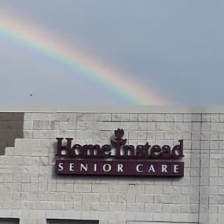 A beautiful rainbow arches over the Home Instead Senior Care building.