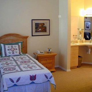 A cozy bedroom with a single bed, decorative quilt, and an adjacent sink area.