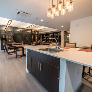 A modern kitchen with an island and dining area featuring elegant lighting.